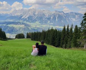 a man and woman sitting in a field looking at the mountains at Apartment Lina in Gröbming