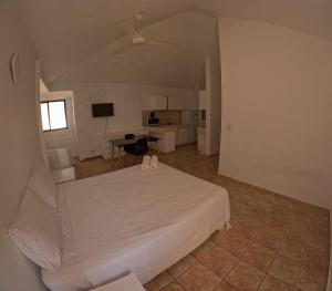 a large bedroom with a white bed and a kitchen at Hotel El Legendario in Sosúa