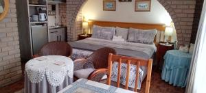 Schlafzimmer mit einem Bett mit 2 Stühlen und einem Tisch in der Unterkunft Lily's Cottage in Durban