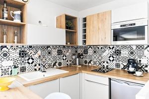 a kitchen with black and white tile on the wall at Barri furnished flat in Cagnes-sur-Mer