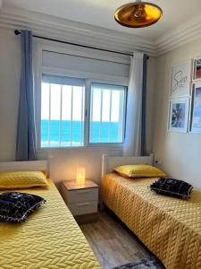 a bedroom with two beds and a window with the ocean at Ocean view sunset apartment in the heart of Rabat in Rabat
