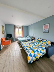 um quarto com 2 camas e uma cadeira laranja em Oslo - Appartement Spacieux et Cosy em Charleville-Mézières