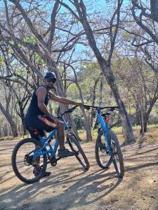 a man riding a blue bike on a dirt road at Casa Jungla Playa Avellanas in Río Sequito