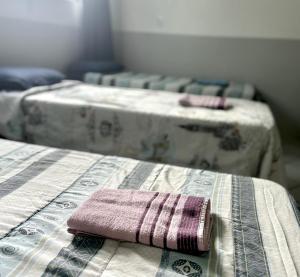 two beds in a room with a towel on a table at Hotelcity in Brusque