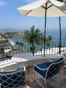 uma mesa e cadeiras com um guarda-sol e o oceano em Departamento familiar con vista al mar em Manzanillo