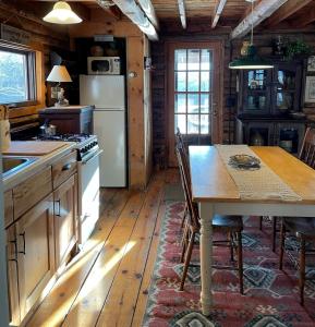 uma cozinha com uma mesa e um frigorífico em Cozy Cottage on Pond em Great Valley
