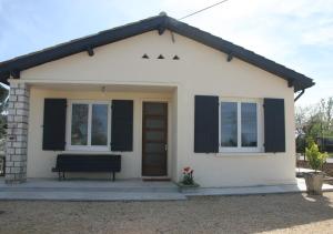 uma pequena casa branca com um banco à frente em GITE chez mamie - 7 personnes A SAINTE LIVRADE SUR LOT em Sainte-Livrade-sur-Lot