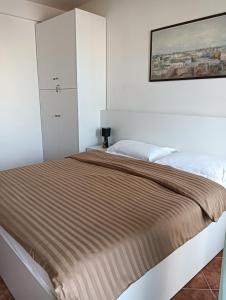 een witte slaapkamer met een bed en een schilderij aan de muur bij Seaside Deluxe Apartment in Durrës