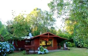 a small red cabin with a bench in the yard at Parcela Peumayen in Licán Ray