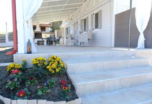 a porch with stairs and flowers in a flower bed at Sunset Beach House in Nea Potidaea