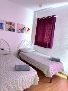 2 camas en una habitación con cortinas moradas en Casa Adosada Bel Andalus, en Estepona