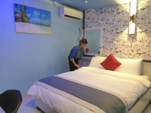 a man standing next to a bed in a room at Isle inn {Fuvahmulah) in Fuvahmulah