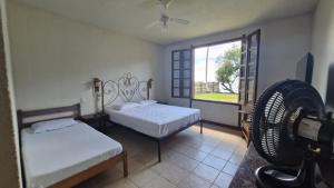 Zimmer mit 2 Betten, einem Ventilator und einem Fenster in der Unterkunft Sítio Santa Cruz in Santa Cruz