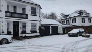 a snow covered street with two houses and a car at Sussex Lodge Guest House in Slough