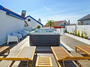 a hot tub on a patio with wooden benches at Maty's Place in Mafra