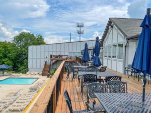 a deck with tables and umbrellas and a pool at Large home in community w/pools&skiing in Bushkill