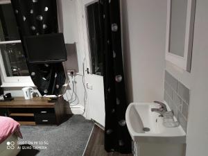 a bathroom with a sink and a tv in a room at Sussex Lodge Guest House in Slough