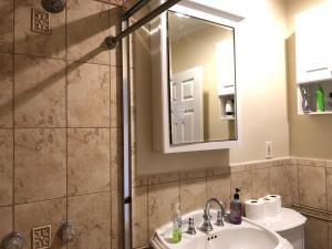 ein Bad mit einem Waschbecken und einer Dusche mit einem Spiegel in der Unterkunft Venice Beach Garden Boutique Guesthouse in Los Angeles