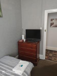 a bedroom with a bed and a television on a dresser at Sussex Lodge Guest House in Slough