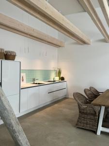 a kitchen with white cabinets and a table and chairs at Sievershof Poolloft in Wietzendorf