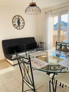 uma mesa e cadeiras numa sala de estar com um relógio em Appartement très lumineux au cœur du massif de la Sainte Baume em Plan dʼAups