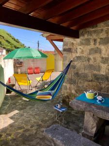 a hammock and chairs and a table and an umbrella at Casa Auri in Faial da Terra