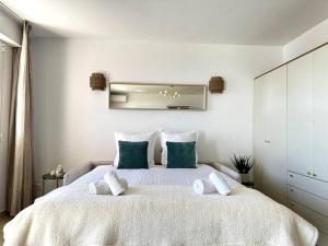 um quarto branco com uma cama grande e almofadas azuis em Monte Carlo Vista - Vue Mer - Terrasse em Beausoleil