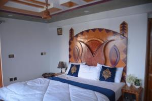 a bedroom with a large bed with a wooden headboard at Eagle Nest Cottage, Kala Bagh in Nathia Gali