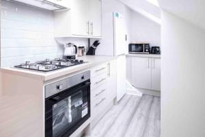 uma cozinha com armários brancos e um forno com placa de fogão em Bright 2-bed Flat in Central Reading em Reading