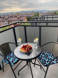 a table with a bowl of fruit and wine glasses on a balcony at Apartament Browarna in Nowy Sącz