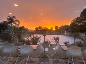 eine Gruppe von Stühlen, die bei Sonnenuntergang am Pool sitzen in der Unterkunft MOBIL HOME saint Raphael camping l’île d’or in Saint-Raphaël