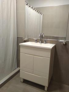 een badkamer met een witte wastafel en een douche bij Apartamentos Anahí in Villa Parque Siquiman