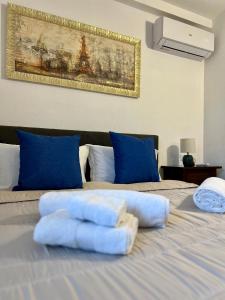 two towels on a bed with blue pillows at Villa Grecale in Cala Liberotto