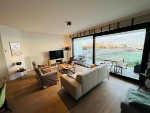 een woonkamer met een bank en een groot raam bij Ruim en modern appartement ideaal gelegen tussen zee en jachthaven in Nieuwpoort