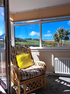 wiklinowe krzesło z żółtą poduszką siedzącą przed oknem w obiekcie Leafield Holiday Home w mieście Stranraer