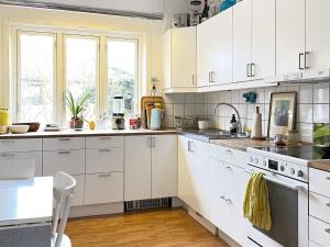 a kitchen with white cabinets and a table at Holiday home HÖGANÄS in Höganäs