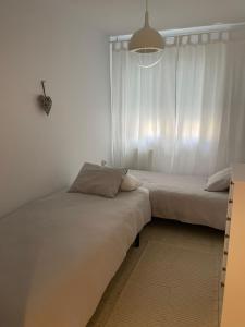 twee bedden in een kamer met witte muren bij Apartamento a pie de playa en Miño in Miño