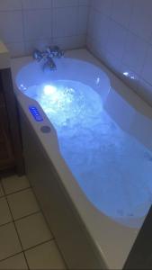 a bath tub filled with blue water in a bathroom at Les pieds dans le sable in Malo-les-Bains