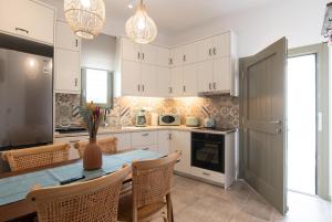 a kitchen with white cabinets and a table with chairs at aerie home Skyros in Skiros