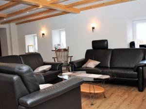 a living room with black leather couches and a table at Eifeler farmhouse in Plütscheid
