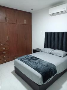 a bedroom with a large bed and wooden cabinets at Departamento cerca de la Universidad de Montemorelos in Montemorelos