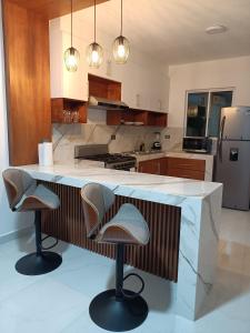 a kitchen with a counter with two stools in it at Departamento cerca de la Universidad de Montemorelos in Montemorelos