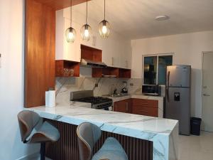 a kitchen with a refrigerator and a counter with chairs at Departamento cerca de la Universidad de Montemorelos in Montemorelos