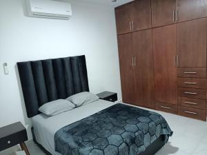 a bedroom with a bed with a black headboard and wooden cabinets at Departamento cerca de la Universidad de Montemorelos in Montemorelos