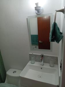 a bathroom with a sink and a toilet and a mirror at Departamento cerca de la Universidad de Montemorelos in Montemorelos