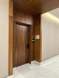 リヤドにあるLuxury condo in almalqa near Boulevardの看板のある建物内の木製ドア