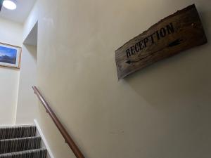 un cartel de madera en una pared de una escalera en The Old Bank House Hotel, en Grouville