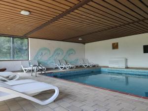 a swimming pool with white chairs and a swimming pool at Ferien vom Ich, Bayerischer Wald, Hotel & Restaurant in Neukirchen