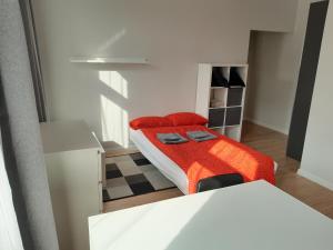 カトヴィツェにあるConcordia Apartmentの赤い毛布付きのベッドが備わる小さな客室です。