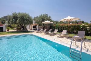 una piscina con sillas y sombrillas en un patio en Skales Villas, en Almiros Beach